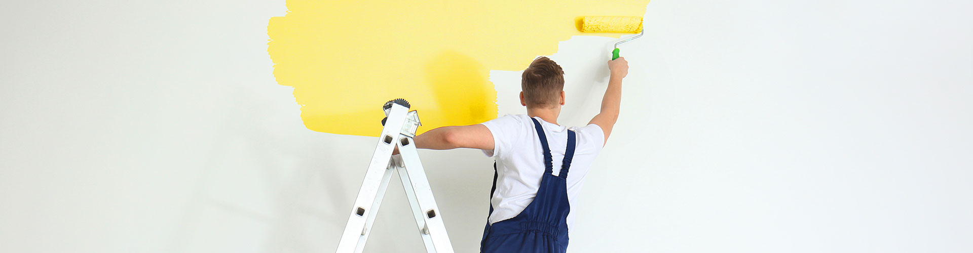 Painting contractor rolling wall of building